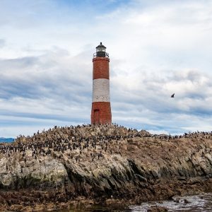 Vista del Faro Les Éclaireurs, el "Faro del Fin del Mundo", rodeado de cormoranes en un islote del Canal Beagle, Ushuaia.