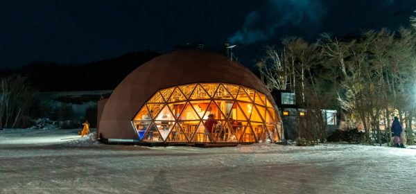 Domo geodésico iluminado en el centro invernal Husky Park en Ushuaia, rodeado de nieve y bosque nativo en plena noche invernal.