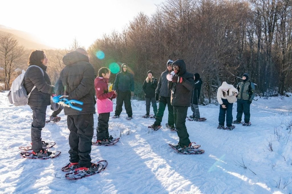 Guía de turismo explicando las instrucciones a un grupo de visitantes equipados con raquetas de nieve en Park Austral.