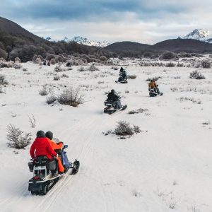Grupo en motos de nieve recorriendo valle nevado en Ushuaia. Excursión de invierno.