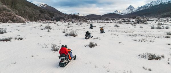Grupo en motos de nieve recorriendo valle nevado en Ushuaia. Excursión de invierno.