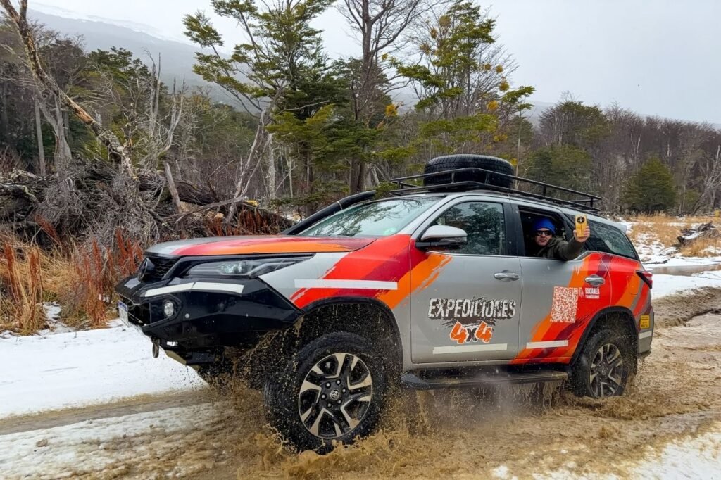Conductor de la camioneta 4x4 saludando por la ventana mientras maneja en el barro y la nieve.