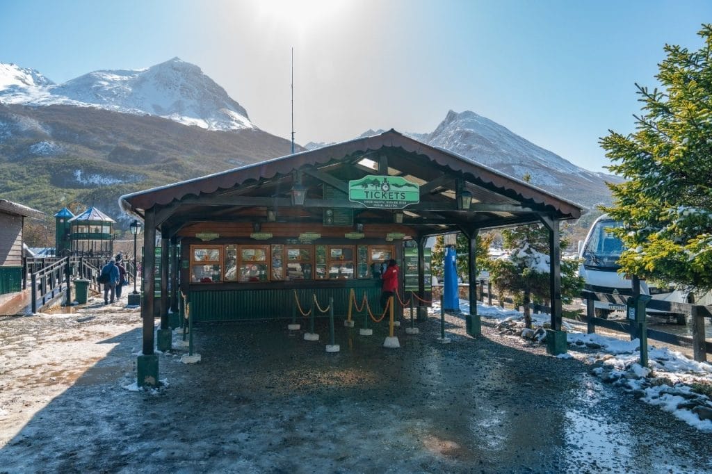 Boletería exterior de la Estación del Tren del Fin del Mundo con montañas nevadas de fondo en Ushuaia.
