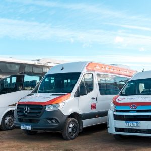 Flota de vehículos de transporte de la agencia Aswalek en Ushuaia, que incluye un minibús Agrale, un furgón Mercedes-Benz Sprinter y una minivan Toyota Hiace, estacionados frente a montañas nevadas.