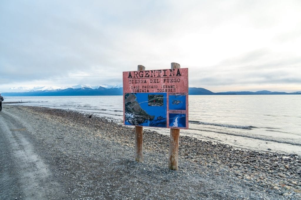 Cartel de madera de Tierra del Fuego en la playa de piedras a la orilla del Lago Fagnano en Ushuaia.