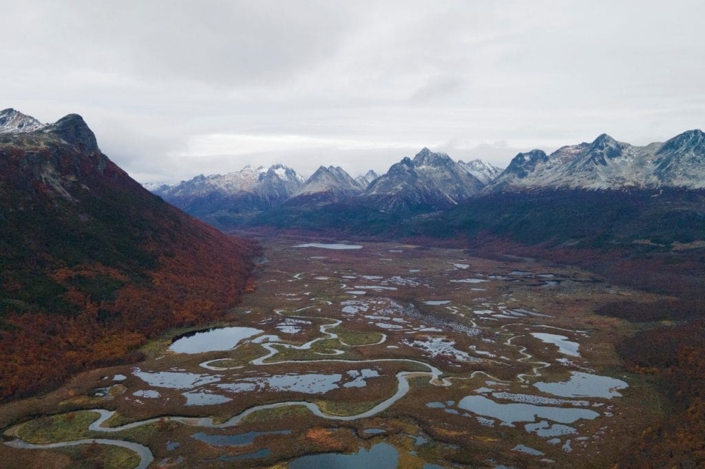 Vista aérea del Valle Carbajal en otoño con turberas, ríos serpenteantes y bosques de lengas rojas en Ushuaia.