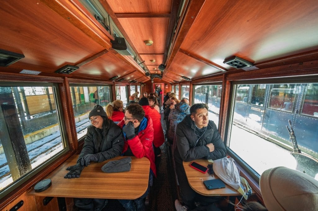 Interior de los vagones de madera del Tren del Fin del Mundo con pasajeros disfrutando del viaje en Ushuaia.