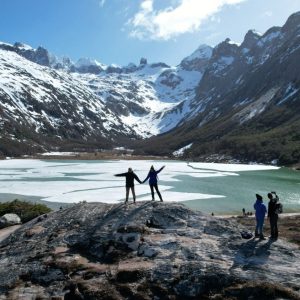 Pareja disfrutando la vista panorámica de la Laguna Esmeralda congelada y montañas nevadas durante el Trekking Laguna Esmeralda