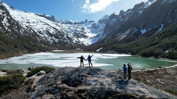 Pareja disfrutando la vista panorámica de la Laguna Esmeralda congelada y montañas nevadas durante el Trekking Laguna Esmeralda