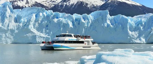 Catamarán navegando en un campo de témpanos de hielo frente al glaciar.
