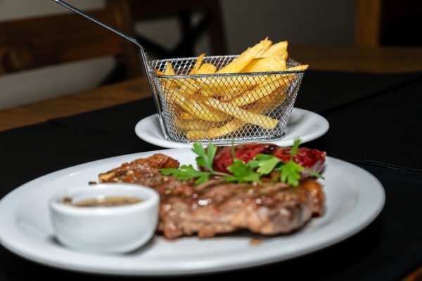 Bife de chorizo con chimichurri y una canasta de papas fritas crocantes en el refugio de montaña en Ushuaia.