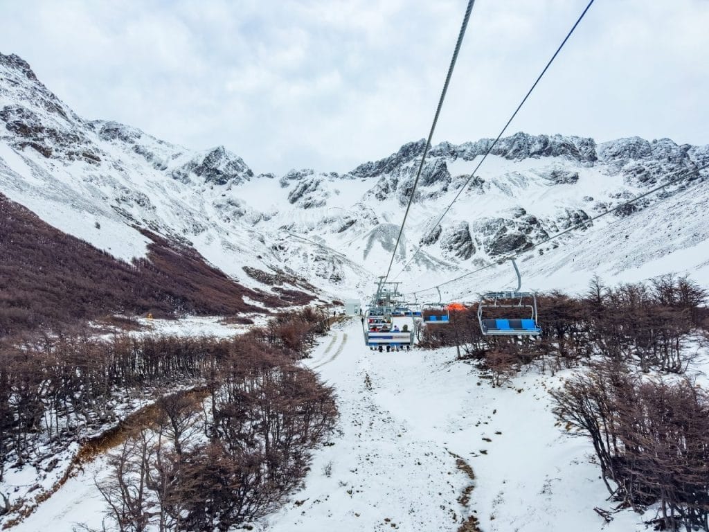 Vista panorámica desde la aerosilla del Glaciar Martial, Ushuaia, mostrando la subida por un valle nevado hacia las montañas andinas bajo un cielo nublado.