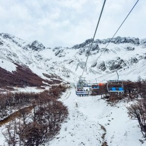 Vista panorámica desde la aerosilla del Glaciar Martial, Ushuaia, mostrando la subida por un valle nevado hacia las montañas andinas bajo un cielo nublado.