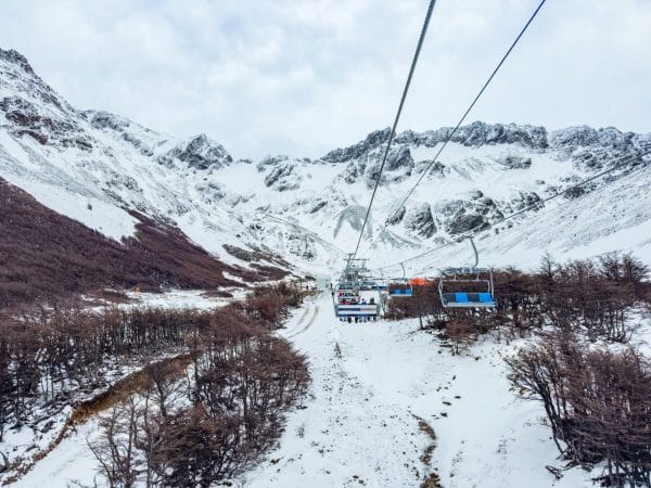 Vista panorámica desde la aerosilla del Glaciar Martial, Ushuaia, mostrando la subida por un valle nevado hacia las montañas andinas bajo un cielo nublado.