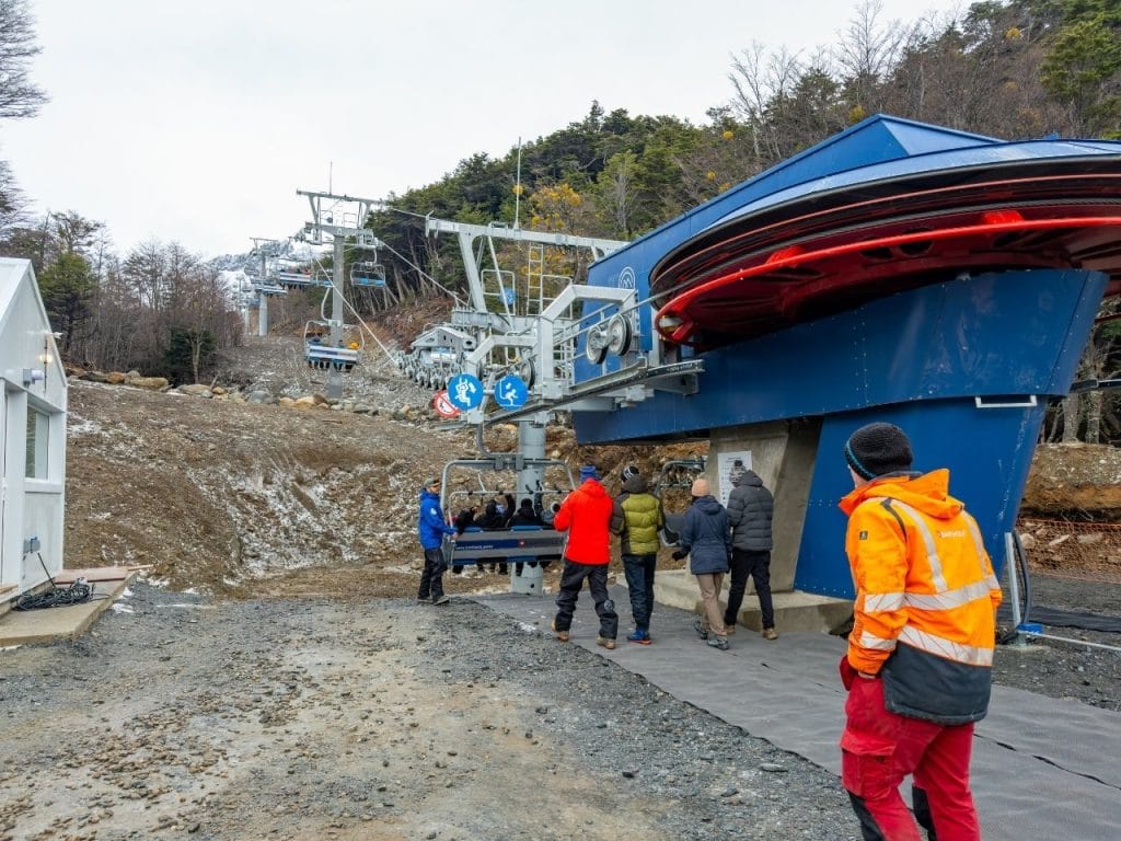 Estación de base de la aerosilla del Glaciar Martial con el mecanismo mecánico expuesto, operadores y pasajeros en Ushuaia, Tierra del Fuego.